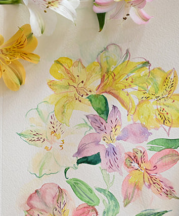 Floral drawing on a notebook with flowers and brushes on top